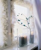 Winterliche Fensterdeko: weiße Feder boa, Kerzen u. Zweig im Glas