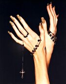 Close-up of woman's hand wearing colourful nail polish holding rosary