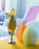 Goose egg decorated with green and golden ribbon on silver egg cup