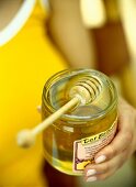 Close-up of honey dipper with jar of honey