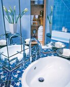 Blauer Mosaik-Waschtisch mit einem Spiegelschrank hinter der Armatur