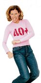 Hüpfende Frau trägt rosafarbenes T-Shirt mit "40 +"- Aufdruck