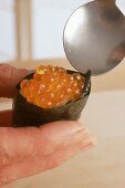 Reisgefülltes Noriblatt darauf einen Klacks Forellenkaviar verteilen