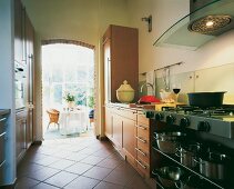 View of open kitchen with sleek maple furniture and stainless steel utensils