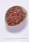 Roter Reis; rohe Körner in einer hellgrünen Keramikschale