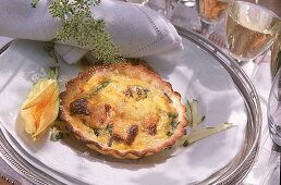 Quiche mit Zucchini, auf weißen Teller mit Zucchiniblüte