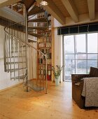 Wendeltreppe aus Edelstahl, dahinter ein Bücherregal überbeide Stockwerke