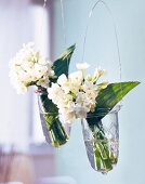 weiße, frühlingshafte Blüten in 2 Hängevasen aus Glas