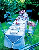 Romantic table laid with antique dishes and glasses in garden