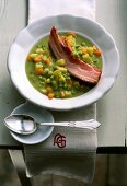 Pea soup with root vegetables, potatoes and pork on plate