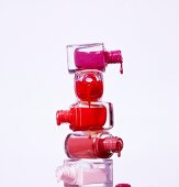 Stack of dripping nail polish bottles against white background