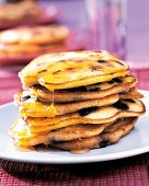 Pancakes mit Heidelbeeren im Teig und Honig, übereinander gestapelt.