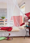 Zimmer mit Eisenbett, Rosen-Bettwäsche, Moskitonetz, rote Wände