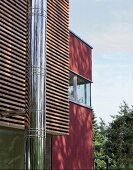 Moderne Fassade; Leistenverkleidung, rote Mauer + Edelstahlschornstein