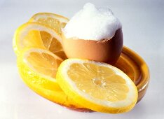 Slices of lemon and whipped egg white in broken egg shell