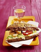 Puten-Sandwich auf weißer Serviette und ein  Glas Wasser auf Tablett