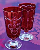 Close-up of two red crystal glasses engraved with vine and flower ornaments