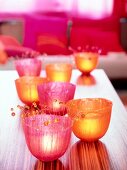 Several pink and orange lanterns on wooden table