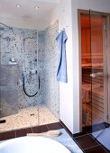 Eine Dusche mit blauen Mosaikfliesen und daneben eine Sauna