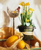 Daffodils in vase, wooden rooster and decorated eggs on table