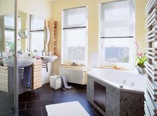 Interior of bathroom with yellow walls, white whirlpool bathtub and sink