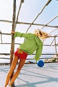 Frau spielt mit Ball, sportlich bunt gekleidet, sommerlich, Rückenansicht