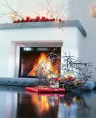 Nest with red and golden baubles in front of fireplace with candles on mantel