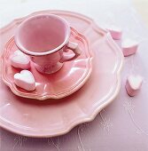 Tasse mit Untertasse und Kuchenteller in rosa