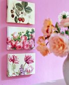 Three small paintings with floral motifs on pink wall