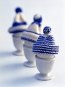 Bobble hats on eggs in three egg cup on white background