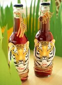 Bottles decorated with jungle characters and artificial leaves on table