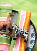 Close-up of multi-coloured napkins with horse and giraffe figures on napkin rings