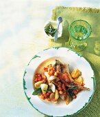 Rabbit leg with onions on plate and glass of water on green table mat