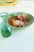 Almond chicken with tomato on plate with green vase on table