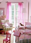 Children's room decorated with pink coloured bed, small chairs and arm chairs