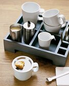 Tablettbox mit mehreren Kaffebechern ,Sahnekännchen und Zuckerdose