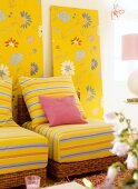 Yellow striped cushions on wicker chair against floral patterned wallpaper