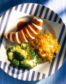 Almond rice with slices of chicken and broccoli on plate, overhead view