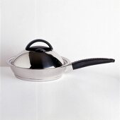 Stainless steel pan with rotating lid on white background