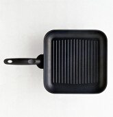 Alpha cast square pan make of serrated stainless steel on white background, overhead view