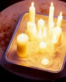 Flackernde Kerzen auf einem Backofen Bräter, mit Vogelsand ausgestreut