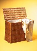 Linen chest basket with cloth on yellow background