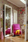 View of room with large mirror, bookcase, chair and floral wallpaper