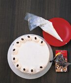 Torte wird mit einem Spritzbeutel mit Sahne und Kaffeebohnen verziert