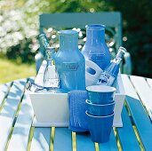 Keramikkaraffen und Geschirr in blau auf einem Tablett in weiß im Garten