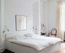 Ein helles Schalfzimmer mit Bett, Louis-XVI-Sessel und einem Bildern