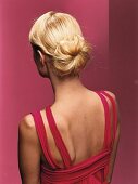 Rear view of blonde woman with inward bun against pink background