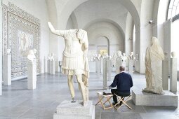 Man sitting in front of sculptures in Glyptothek Museum, Munich, Germany