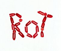 Pieces of red lipstick placed together to form word 'rot' on white background
