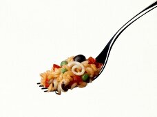 Risotto with black olives and squid on fork against white background